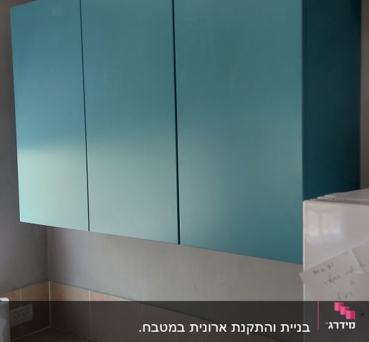 ארונות מטבח כחולים מעל משטח עבודה בהיר
